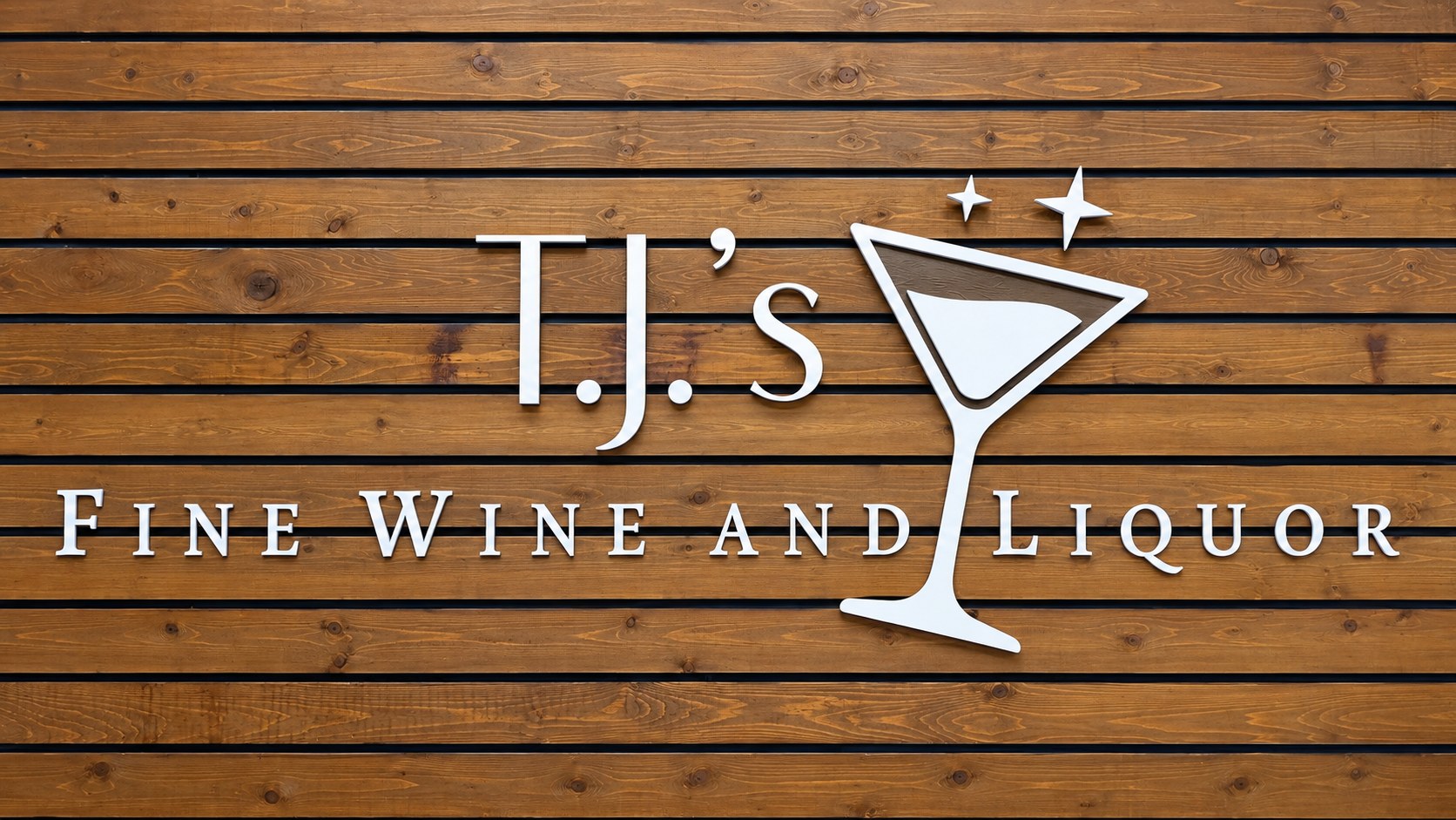 White T.J.'s Fine Wine and Liquor logo on the warm wood wall behind the checkout counter